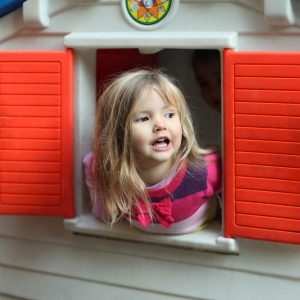 Young girl looking through playhouse window