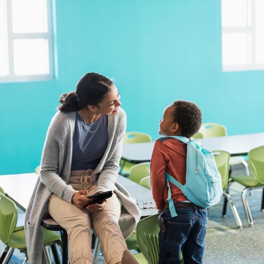 Teacher and young boy talking in class