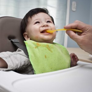 Happy toddler being fed in highchair