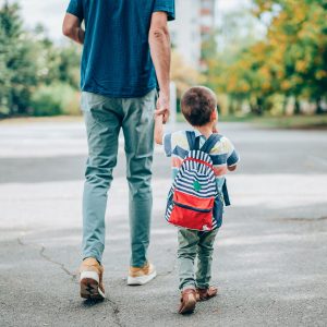 Young boy with backpack holding father’s hand